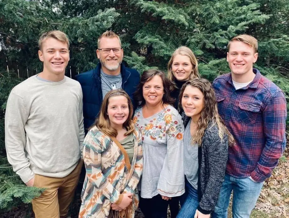 Bill and Shelley Hauter with their five children outdoors under evergreen trees